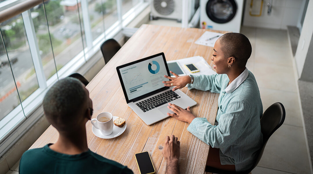 Two people reviewing loan options together at a table with a laptop.